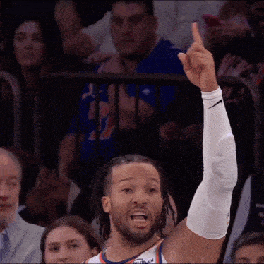 a basketball player wearing a white nike sleeve is giving a thumbs up