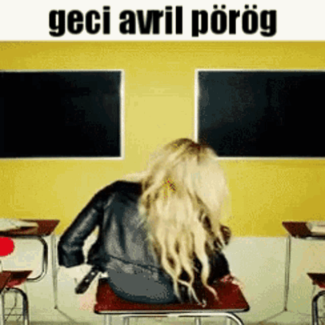 a woman is sitting at a desk in front of a yellow wall with the words " geçi avril porog " written on it