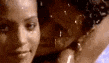 a close up of a woman 's face with water drops on it and a man in the background .