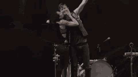 a man and a woman are standing next to each other on a stage holding a microphone .