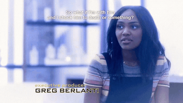 a woman is sitting in front of a sign that says executive producer greg berlanti