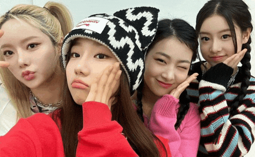 four girls are posing for a picture and one of them is wearing a hat that says ' lg ' on it