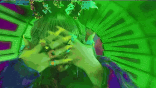 a person covering their face with their hands in a green and purple background