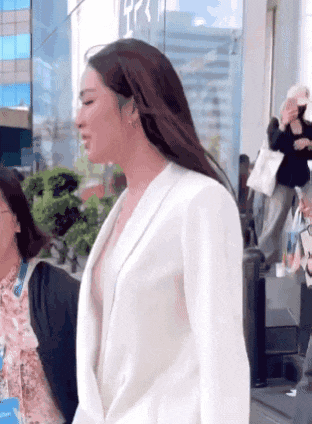 a woman wearing a white jacket is walking down the street .