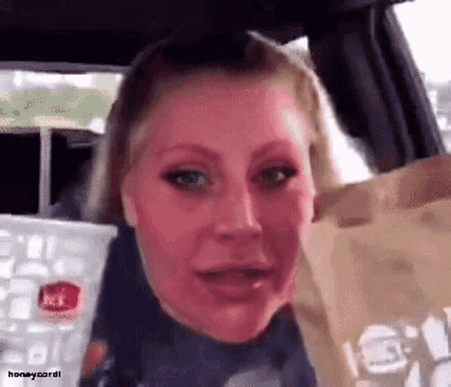 a woman in a car holding a jack in the box cup and bag