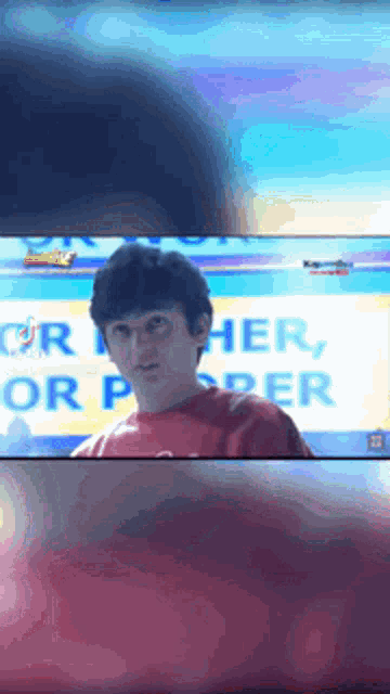 a man in a red shirt stands in front of a sign that says " her or per "