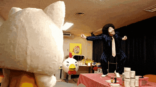 a man in a suit and tie is dancing next to a stuffed animal that looks like a chicken
