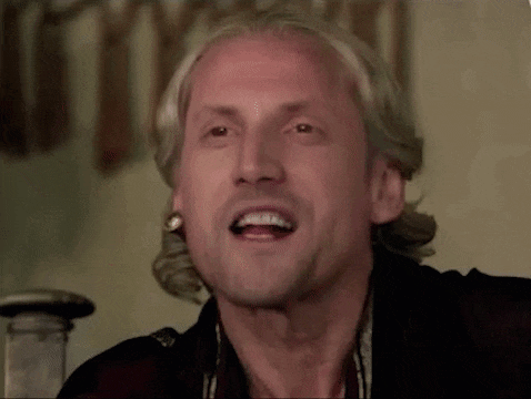 a man with blonde hair is making a funny face while wearing earrings .