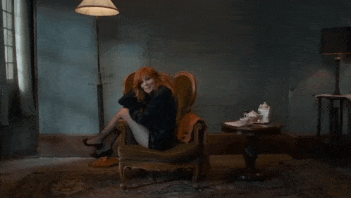 a woman is sitting in a chair in a dark room