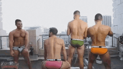 a group of men in underwear are dancing on a rooftop