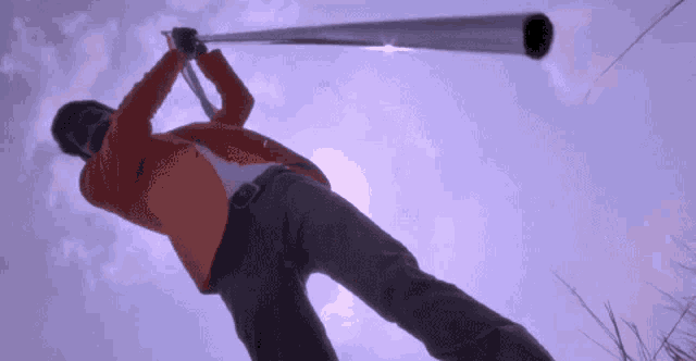 a man in an orange jacket is holding a long pole in the air