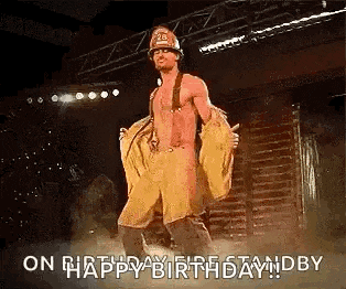 a man dressed as a fireman is dancing on a stage and says `` happy birthday '' .