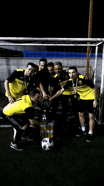 a group of soccer players posing for a picture with a trophy
