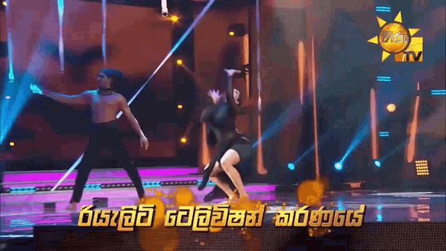 a man and a woman are dancing on a stage in front of a sign that says ' sun tv '