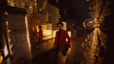 a man in a red jacket and top hat is standing in front of a gold wall