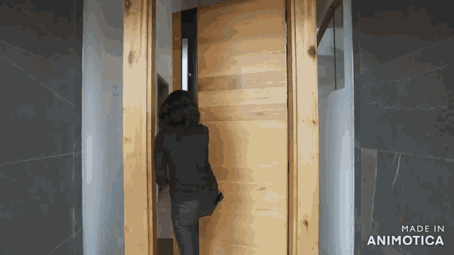 a woman is walking through a wooden door with the words made in animatica on the bottom