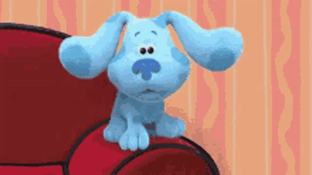 a blue cartoon dog is sitting on a red couch