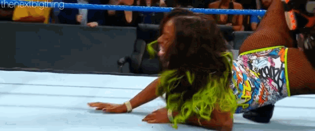 a female wrestler is laying on the floor in a wrestling ring with the text " thenextbigthing " on the bottom