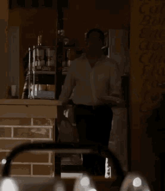 a man in a white shirt and black pants holds a plate in front of a sign that says " coca cola "