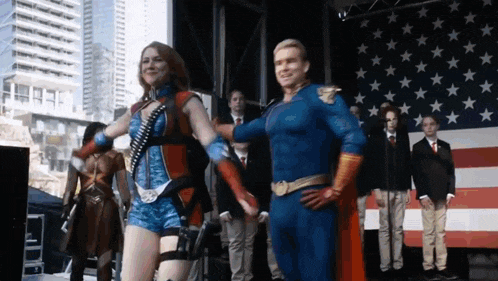 a man in a superhero costume is standing next to a woman in a superhero costume on a stage .