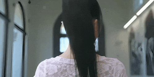 a woman with long black hair is wearing a white lace top and earrings .