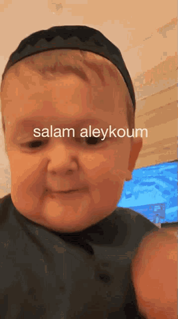 a baby wearing a black headband with the words salam aleykoum written on it