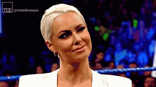 a woman in a white jacket is standing in a wrestling ring .