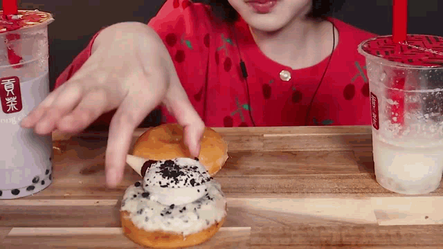 a woman in a red shirt is eating a donut next to a cup that says coca cola