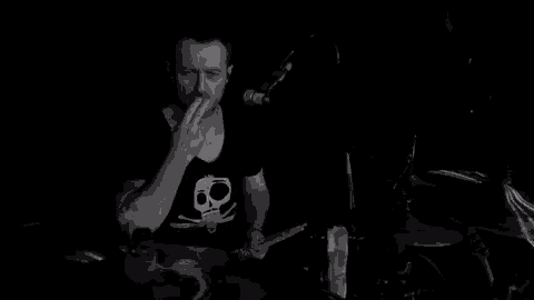 a man is playing drums in front of a microphone in a dark room .