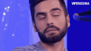 a man with a beard is standing in front of a microphone with his eyes closed and the words viperissima above him