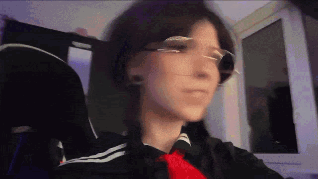 a girl wearing glasses and a red tie is sitting in a chair