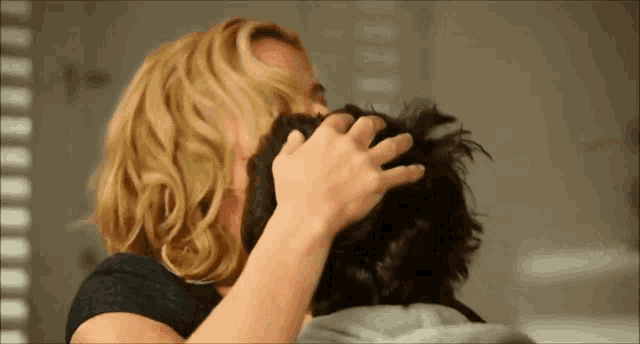 a woman touches a man 's head with her hand