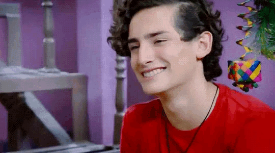 a young man in a red shirt is smiling