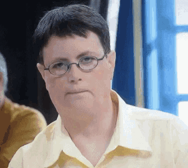 a man wearing glasses and a yellow shirt is making a funny face