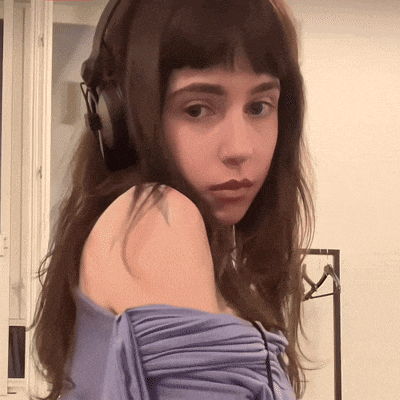 a woman wearing headphones and a blue shirt looks at the camera