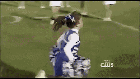 a little girl in a cheerleading uniform is holding pom poms on a football field .