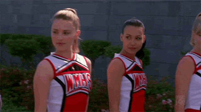 three cheerleaders wearing wmhs uniforms are standing in a line