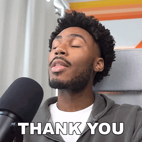 a man singing into a microphone with the words thank you behind him