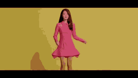 a woman in a pink dress is standing in front of a yellow background .