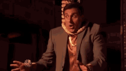 a man in a suit with a lei around his neck is holding something in his hand .