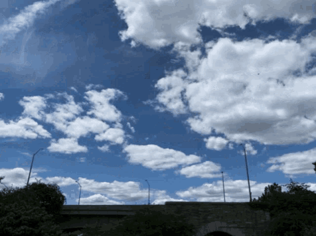 a bridge with a blue sky and white clouds above it