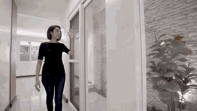 a woman standing in a hallway with a plant in front of her