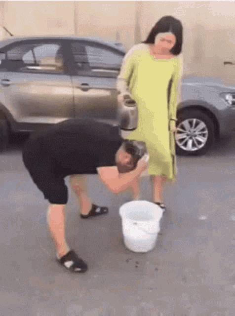 a woman is pouring water into a man 's face