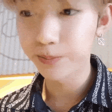 a close up of a person 's face wearing earrings and a striped shirt .