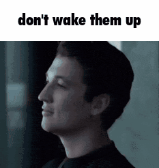 a man is standing in front of a window with the words `` don 't wake them up '' written on the bottom .