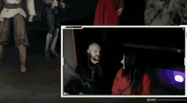 a man and a woman are sitting in front of a microphone in a dark room ..