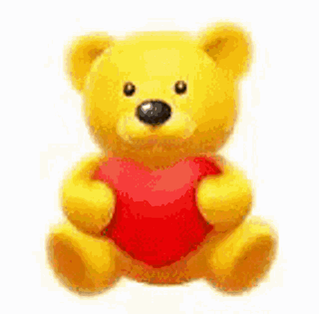 a yellow teddy bear holding a red heart in its paws .