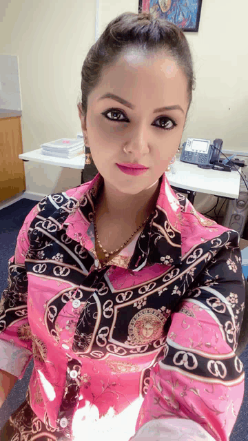 a woman is wearing a pink shirt with a black and gold pattern