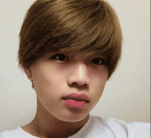 a close up of a young man 's face with a white shirt on