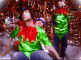 a man in a green and red elf costume is standing next to another man in a blue hat .